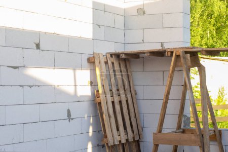 Foto de Andamios de madera sobre el fondo de una casa de bloques de gas en construcción. - Imagen libre de derechos