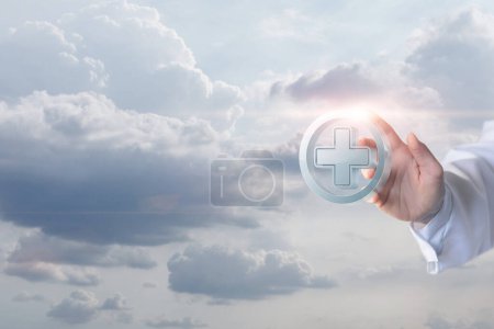 Foto de El médico hace clic en una cruz sobre un fondo borroso del cielo. - Imagen libre de derechos