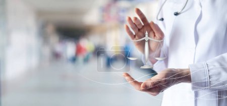 Téléchargez les photos : Le médecin montre des échelles de justice sur fond d'hôpital flou. - en image libre de droit