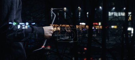 Foto de Un ladrón con una palanca se prepara para entrar en una tienda de la ciudad por la noche.. - Imagen libre de derechos