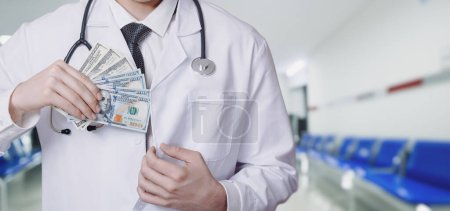 Téléchargez les photos : Docteur met des billets de dollar dans sa poche latérale sur un fond flou. - en image libre de droit