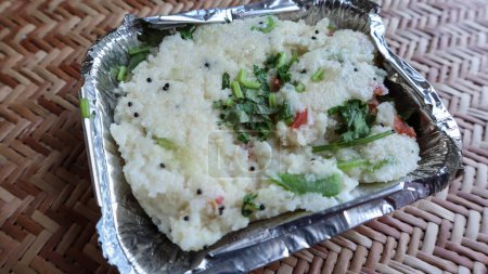 Téléchargez les photos : Populaire petit déjeuner indien du sud Upma petit déjeuner colis alimentaire dans un récipient jetable à emporter. Rava upma garni de feuilles de coriandre fraîche - en image libre de droit