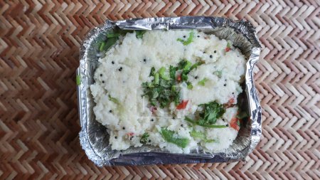 Delicious Upma breakfast food parcel in disposable container take away. Rava upma garnished with fresh coriander leaves