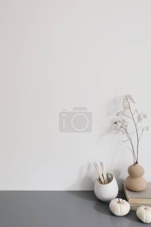Photo for Artistic wokspace, still life. Pencils in ceramic holder. Vase with dry lunaria flowers, litttle white pumpkins, books. Grey table. Creative table background, Autumn, winter home office decor, space - Royalty Free Image