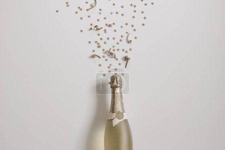 Happy new year still life. Bottle of champagne wine and star shape golden confetti isolated on beige table background. Birthday, party celebration and anniversary. Alcoholic drink, flat lay, top view.