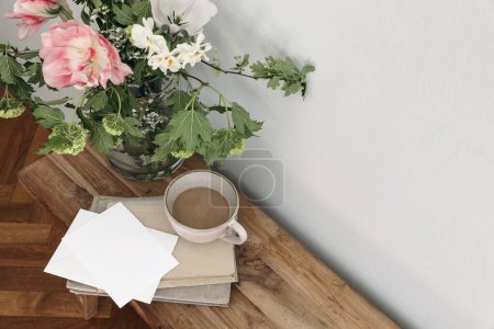 Photo for Spring wedding still life. Floral bouquet. Tulips, guelder rose and daffodil flowers. Empty paper card, invitation mockup on vintage bench. Cup of coffee, old books, blurred wooden floor background. - Royalty Free Image