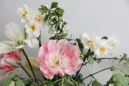 Photo for Spring bridal bouquet of mixed garden flowers on vintage gray wall background behind. Closeup of pink tulip, daffodils and green guelder rose branches. Selective focus. Wedding, birthday. Mothers day. - Royalty Free Image