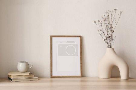 Photo for Elegant boho still life. Modern vase with dry grass on table, desk. Empty wooden picture frame mockup. Cup of coffee, books. Artistic poster display, minimal home interior. Home office desk. - Royalty Free Image