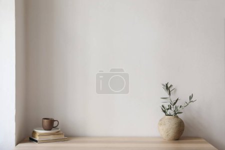 Photo for Elegant Mediterranean interior. Vintage vase with olive tree branches, cup of coffee. Books on wooden table. Living room still life. Empty wall copy space, modern home, apartement design, no people. - Royalty Free Image