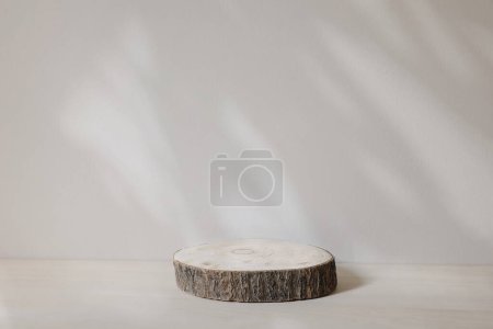 Photo for Wooden disc, podium lies on trendy beige background in sunlight. White wall background. Flower, leaves shadows. Platform, pedestal for luxury, natural cosmetics, wood tray mockup, products - Royalty Free Image