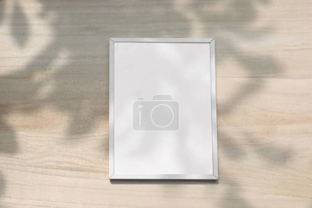 Photo for Summer mockup. Blank vertical picture frame hanging on beige wooden wall in sunlight. Dark blurred leaves, tree branches silhouette shadows overlays. Empty poster mock-up for art display, copy space. - Royalty Free Image