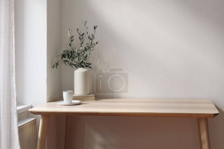 Photo for Mediterranean home interior. Vintage vase with olive tree branches, cup of coffee. Books on wooden table. Living room in sunlight. Empty wall copy space, modern summer apartement design. - Royalty Free Image