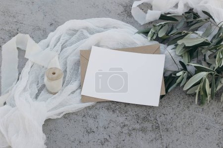 Photo for Mediterranean wedding stationery mock-up still life. Blank greeting card, invitation template. White silk ribbon, table runner. Olive branches, fruit. Grunge concrete background, summer flat lay, top - Royalty Free Image