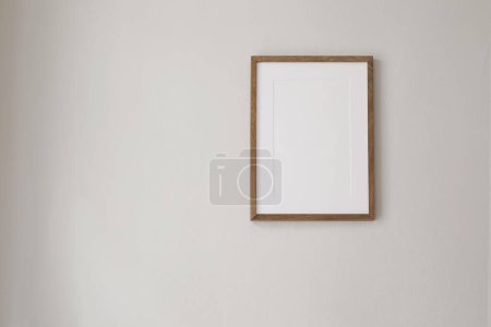 Photo for Vertical wooden picture frame mockup hanging on beige wall. Poster mock-upframe on pastel background in sunlight. Home interior with soft shadow, empty copyspace. Art display concept, minimal interior - Royalty Free Image