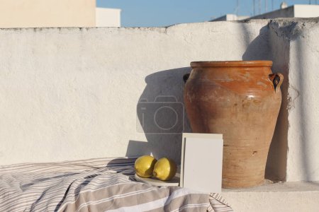 Photo for Summer holiday still life. Blank greeting card, invitation mock up in sunlight. Vintage olive clay pot and fresh lemons fruit. White old textured wall on roof top in sunlight, Mediterranean design. - Royalty Free Image