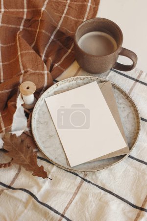 Photo for Autumn background with oak leaf and cup of coffee. Fall greeting card, invitation mockup. Checkered orange and white table cloth. Thanksgiving, Halloween, Vertical flatlay, top view, copy space. - Royalty Free Image