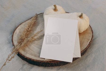 Photo for Autumn, winter stationery still life. Closeup of lank greeting card, invitation mockup on cut wooden round board. Dry grass, little white pumpkins on linen table cloth background, selective focus. - Royalty Free Image