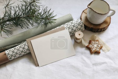 Photo for Christmas still life. Greeting card, invitation mockup. Gingerbread cookies, pine tree branches on white linen table cloth. Gift wrapping papers with green pattern. Milk pitcher, winter stationery. - Royalty Free Image