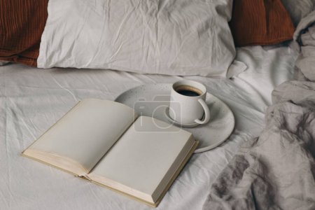Photo for Cup of coffee, open books on white bed sheet. Breakfast in bed concept. Blurred muslin, linen pillows, blanket. Moody cozy Scandinavian bedroom. Top view, no people, lifestyle banner. - Royalty Free Image