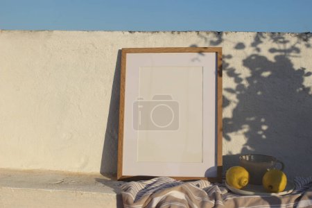 Photo for Vertical wooden frame picture mockup against white old textured white wall in sunlight. Fresh yellow lemons fruit, cup of coffee. Mediterranean summer background with light, floral shadows, blue sky. - Royalty Free Image