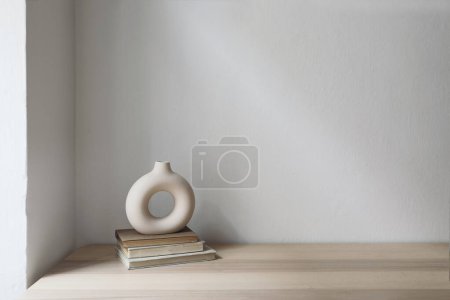 Photo for Elegant neutral still life with modern ceramic vase on old books. Wooden table, desk. White wall background. Empty copyspace, no people. Scandinavian, boho home decor, living room. - Royalty Free Image