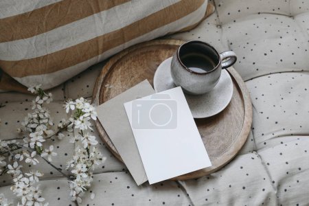 Photo for Spring breakfast scene. Blank greeting card, invitation mockup. Cup of coffee, round wooden tray. Blossoming cherry plum tree branches. Linen sofa polka dot cushion, pillow. Easter, flat lay, top view - Royalty Free Image