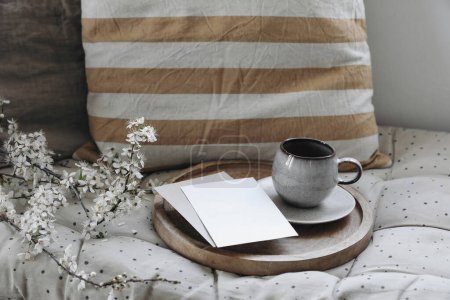 Photo for Moody epring interior still life. Cup of coffee, tea on wooden tray. Blank greeting card, invitation mockup. Blossoming cherry plum tree branch. Sofa with linen cushions, Easter breakfast, home decor. - Royalty Free Image