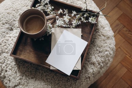 Photo for Spring still life composition. Greeting card mockup, cup of coffee. Feminine photo. Floral scene. Blurred cherry tree blossoms on wool taburet, stool. Defocused wooden parquet floor, top view. - Royalty Free Image