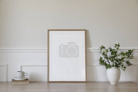 Photo for Springtime breakfast still life. Empty picture frame poster mockup. White ceramic vase with blooming apple tree branches. Cup of coffee, tea on wooden table, desk with old books, scandi home interior - Royalty Free Image
