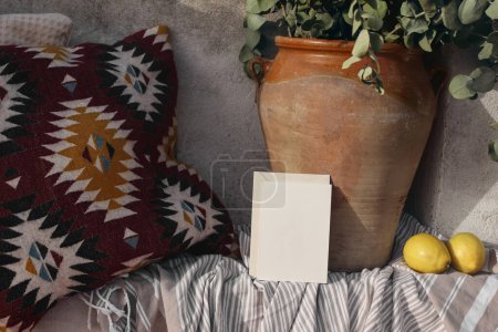 Photo for Blank greeting card, invitation mockup, craft envelope. Summer vacation still life, relaxation concept. Cozy bench with Mexican pattern cushions. Vase, eucalyptus branches, fresh lemons, striped plaid - Royalty Free Image