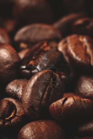 Téléchargez les photos : Vue rapprochée des graines de café brun sur la surface sombre groupe de grains texturés - en image libre de droit