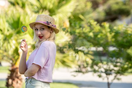 Foto de Linda chica hermosa bonita chica rubia en el sombrero en el verano en el parque con piruleta - Imagen libre de derechos