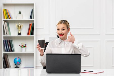 Foto de Servicio al cliente linda chica rubia camisa de oficina con auriculares y computadora que muestra el gesto de llamada - Imagen libre de derechos