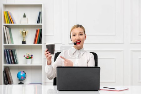 Photo for Customer service cute blonde girl office shirt with headset and computer pointing at coffee cup - Royalty Free Image