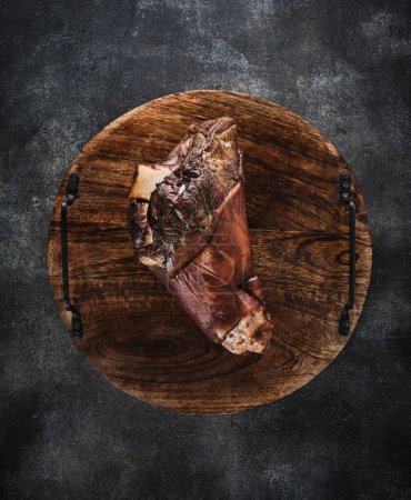 Photo for Smoked knuckle on a wooden board. Top view. - Royalty Free Image