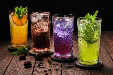 Eine Vielzahl erfrischender Cocktails in verschiedenen Farben, garniert mit frischen Minzblättern, serviert auf einem rustikalen Holztisch