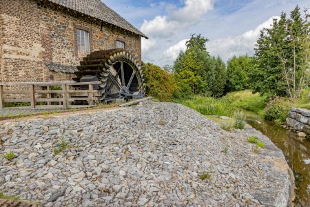 Photo for Stone building with old Eper or Wingbergermolen water mill next to Geul river, two windows, trees and wild vegetation in background, sunny day at Terpoorterweg, Epen, South Limburg, Netherlands - Royalty Free Image