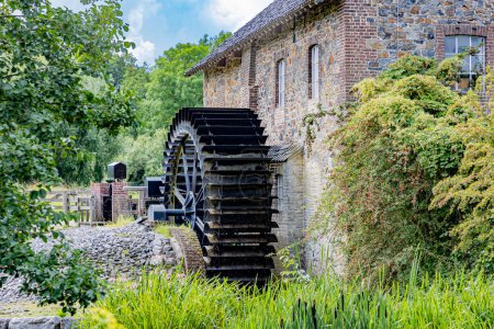 Photo for Old Eper or Wingbergermolen water mill next to stone building, Geul river, wild vegetation and trees in background, sunny day in Terpoorten, Epen, South Limburg, Netherlands - Royalty Free Image