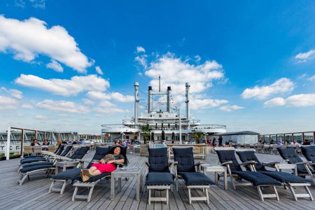 Foto de Rotterdam, Países Bajos, mayo de 2016. Patrón de crucero con sillas para tomar el sol, mujer dormida relajada, piscina y personas disfrutando de un día soleado, cielo azul con nubes de cúmulo blanco - Imagen libre de derechos
