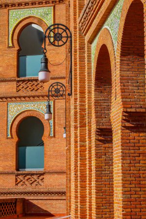 Nahaufnahme von Ziegelwänden mit Säulen und Bogenfenstern, Stierkampfarena Las Ventas im Mudejar-Stil, Hängelampen, sonniger Tag in Madrid, Spanien