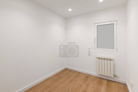 Empty room with frosted glass to avoid watching by neighbours. Laminate flooring and newly painted white walls in refurbished apartment