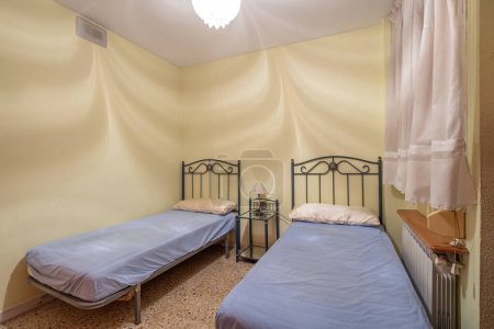 Two beds in a small simple bedroom in a hostel, motel or guest house. Concept of budget accommodation for rent or travel.