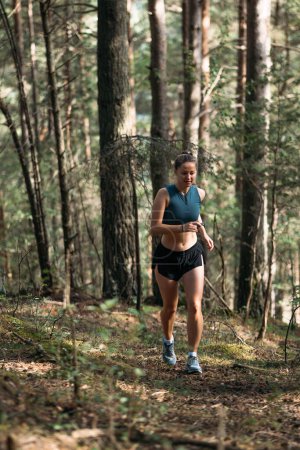Corredor de senderos mujer fitness corriendo en el bosque de verano por la mañana.