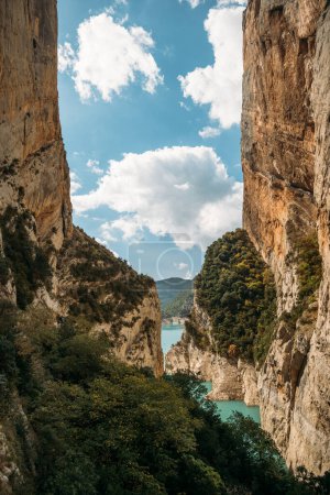 Photo for Blue sky with clouds between narrow rocky cliffs. River in Congost de Mont Rebei gorge in Catalonia, Spain. Natural border between Catalonia and Aragon - Royalty Free Image