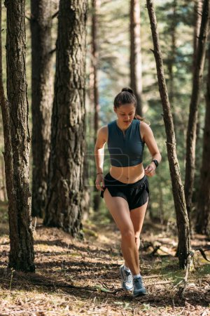 Une jeune femme en tenue de sport aime courir dans la forêt de conifères. La coureuse s'entraîne demain matin. Style de vie sain concept extérieur
