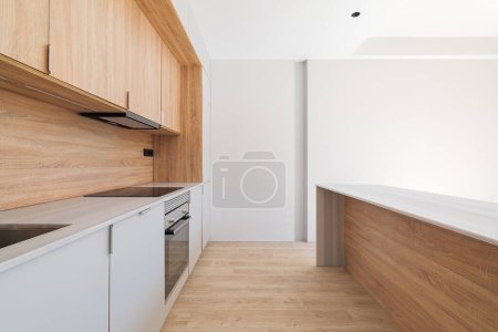 Téléchargez les photos : Intérieur de cuisine moderne avec îlot et meubles en bois. Intérieur vide de lumineux appartement rénové - en image libre de droit