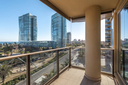 View from a balcony to modern buildings and sunny park in coastal area with sea view, distict Diagonal mar in Barcelona, Spain.