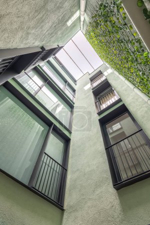 Foto de Vista panorámica del moderno edificio residencial con jardinería vertical en Barcelona. Ventanas de marco negro y paredes verdes - Imagen libre de derechos
