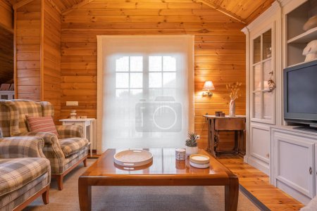 Cozy interior of a country house in a wooden design. Spacious living room with chairs, table and big cupboard.
