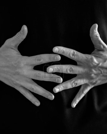 Überlappende Hände schaffen ein kompliziertes Muster vor schwarzem textilen Hintergrund